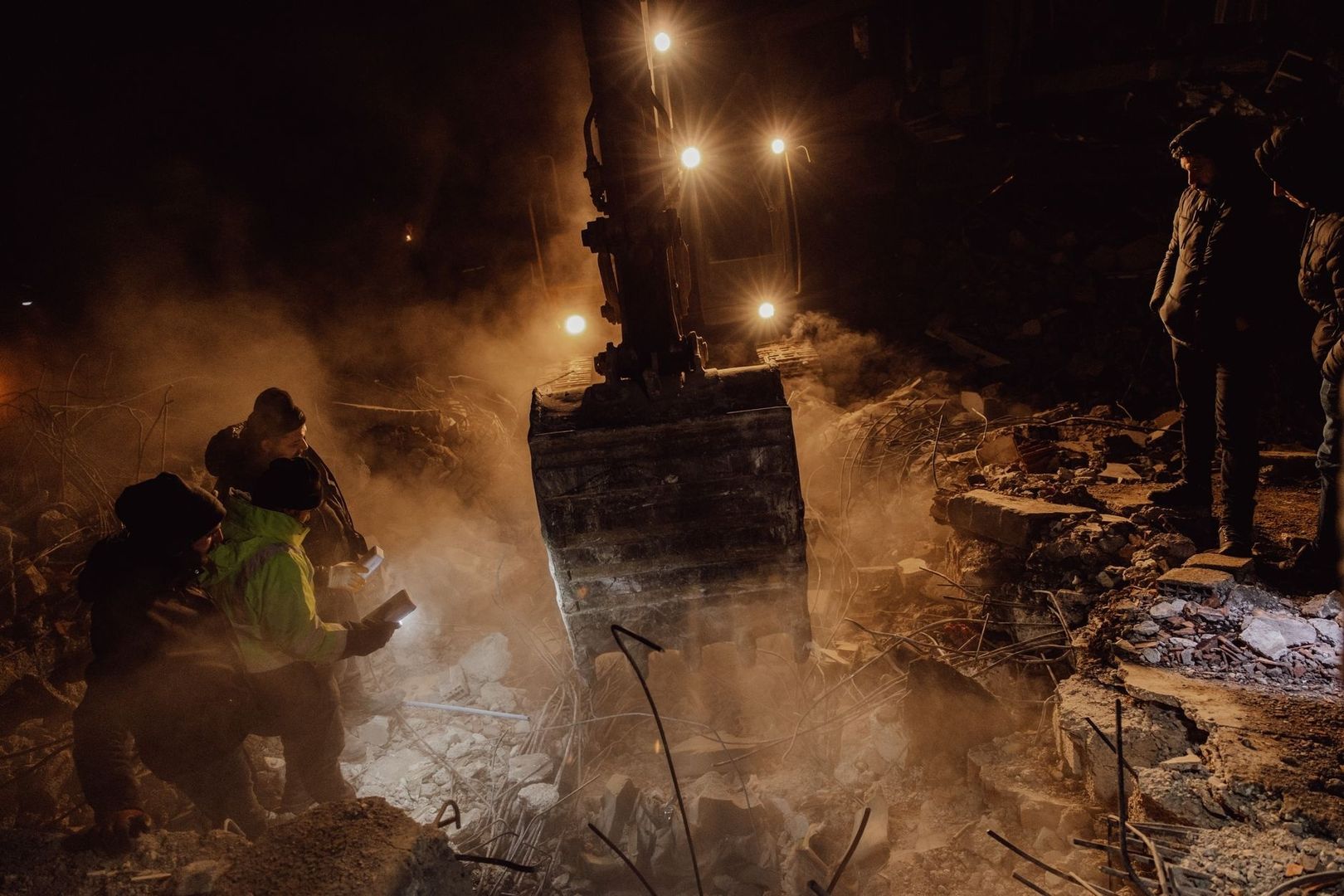 Människor arbetar i ett raserat område under starka arbetslampor
