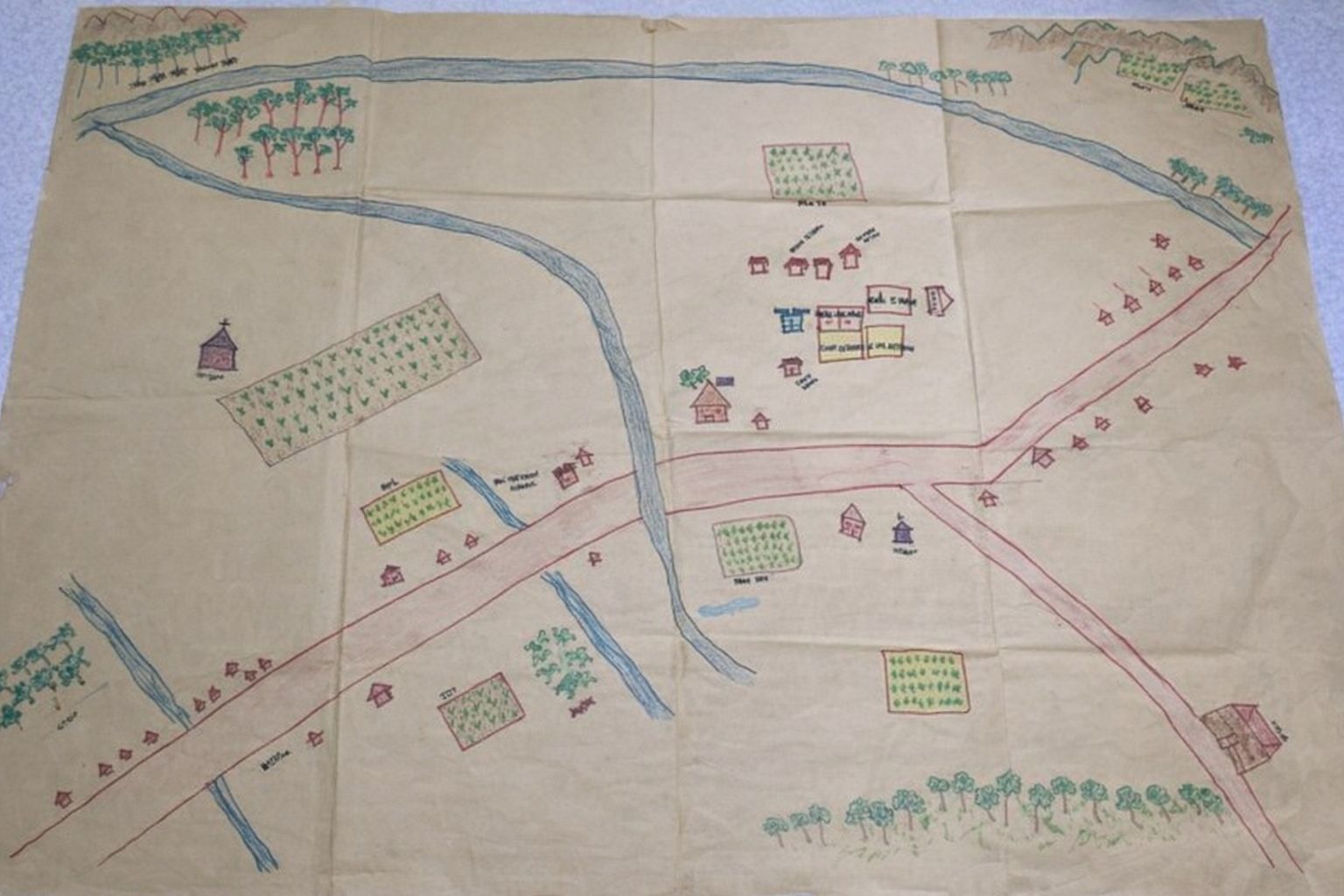 Handritad karta över ett samhälle med floder, vägar, hus och odlingar.